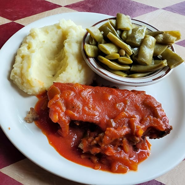 Meatloaf with tomato sauce, mashed potatoes, and green beans on a white plate at Pete's.