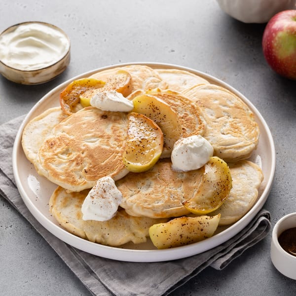 Fluffy pancakes topped with caramelized apple slices, whipped cream, and cinnamon, served at Pete's.